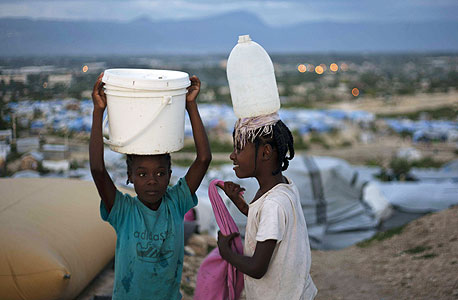 ילדות מובילות מים במחנה פליטים בהאיטי