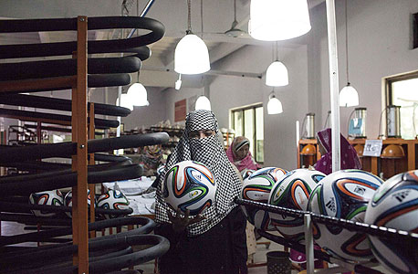 עובדת במפעל כדורים בפקיסטן. 102 דולר לחודש כדי לייצר כדורים שנמכרים ב-100 דולר, צילום: רויטרס