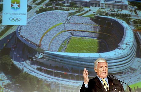 פטריק ראיין עם הדמיית האצטדיון האולימפי. הקשרים עוזרים