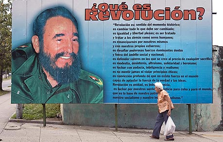 האוונה. אשה צועדת בסמוך לשלט עם תמונה של פידל קסטרו (ארכיון), צילום: בלומברג