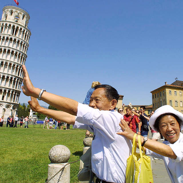 מוסף שבועי 28.6.18 דרקון עם דרכון תיירים סינים על רקע מגדל פיזה איטליה, צילומים: גטי אימג&#39;ס