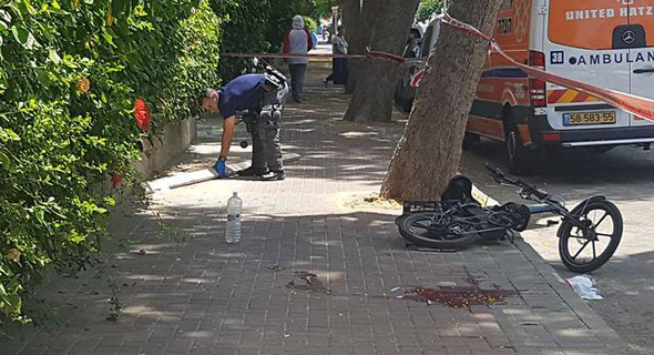 שוטר מרים את הקרש שפגע ברוכב אופניים במקום הארוע שוטר מרים את הקרש שפגע ברוכב אופניים במקום הארוע