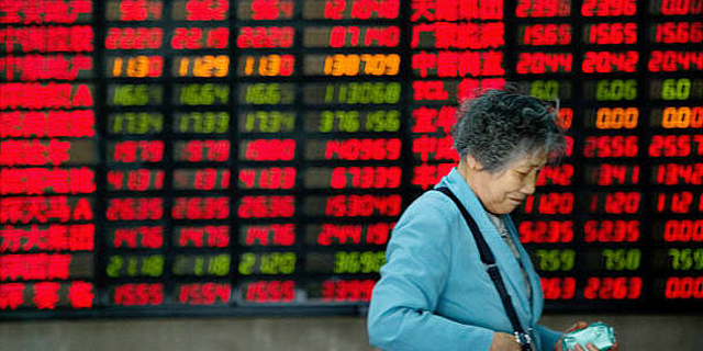 אישה סינית על רקע מסך בבורסה. הדעות חלוקות לגבי מי צריך לנהל את ענייני הכסף במשפחה, צילום: גטי אימג