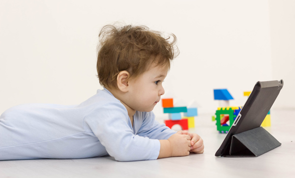 A baby looking at a tablet. Photo: Shutterstock
