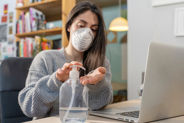  A woman using a hand sanitizer and wearing a mask (illustration). Photo: Shutterstock