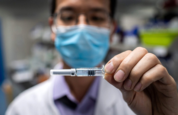 A lab researcher holding up a possible vaccine for Covid-19. Photo: AFP