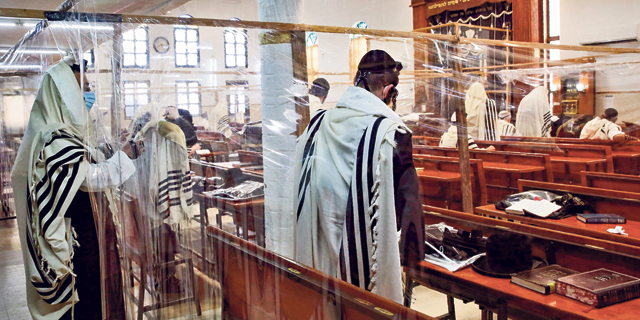 Jewish worshipers praying in an Israeli synagogue separated by nylon Covid-19 barriers during the High Holidays. Photo: AFP