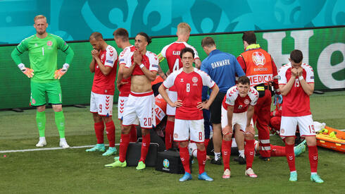 שחקני נבחרת דנמרק מקיפים את אריקסן בזמן הטיפול במגרש שלאחר ההתמוטטות, רויטרס